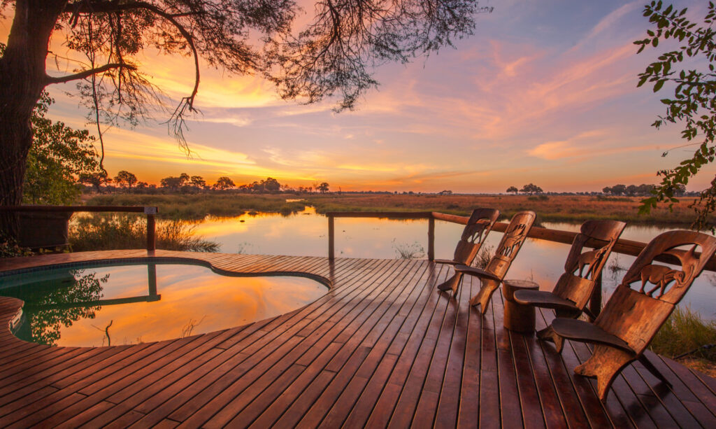 Image of a sunset sky at Lagoon Camp in Botswana reflected in the riverside pool and the river running alongside the camp | Planet Africa Safaris | Blog