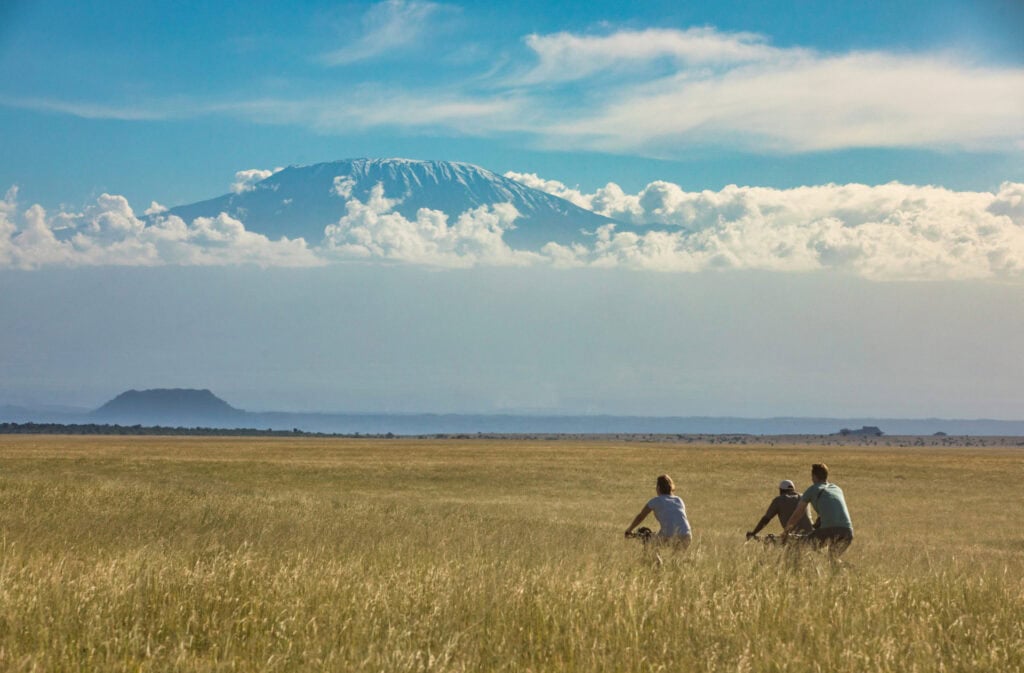 Image of 2 safari-goers and a guide cycling towards the mountains at Ol Donyo in Kenya | Planet Africa Safaris | Blog