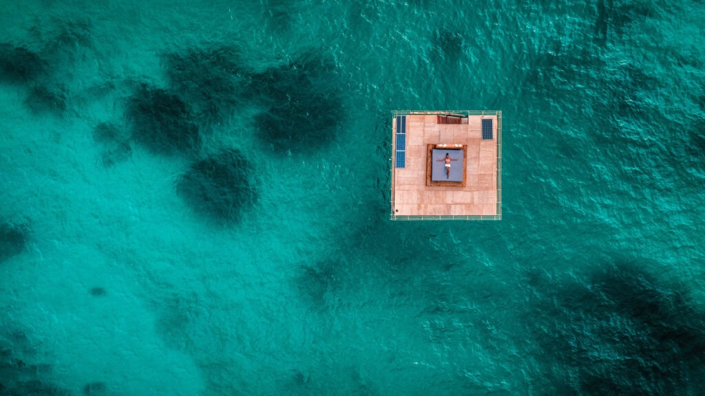 Image of the floating underwater room at Manta Resort on Pemba Island, Tanzania from overhead. Guest can be seen relaxing on a top-level sun tanning bed | Planet Africa Safaris | Blog | Kwanini: The Manta Resort